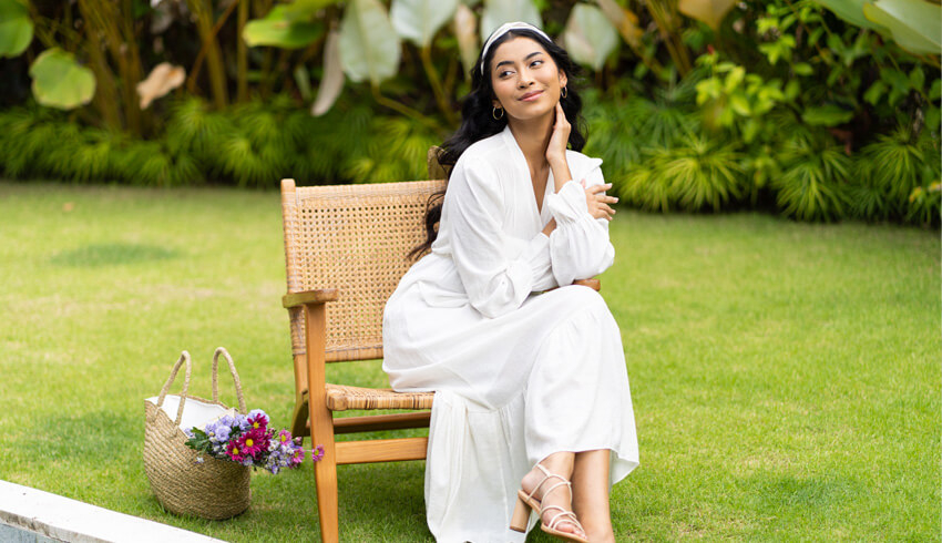 A woman sitting outside on a chair in a garden looking into the distance